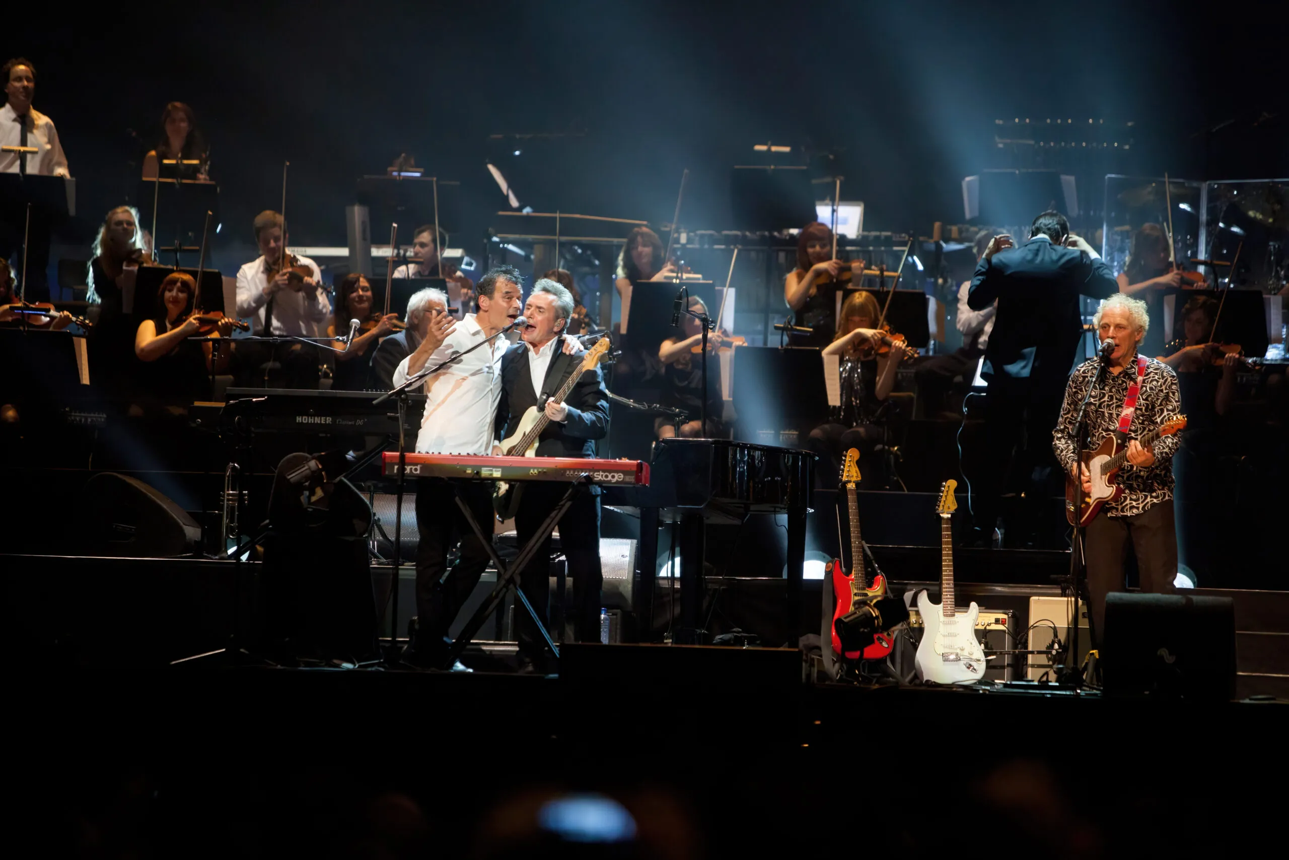 Concertfoto van Doe Maar met volledig orkest op de achtergrond.